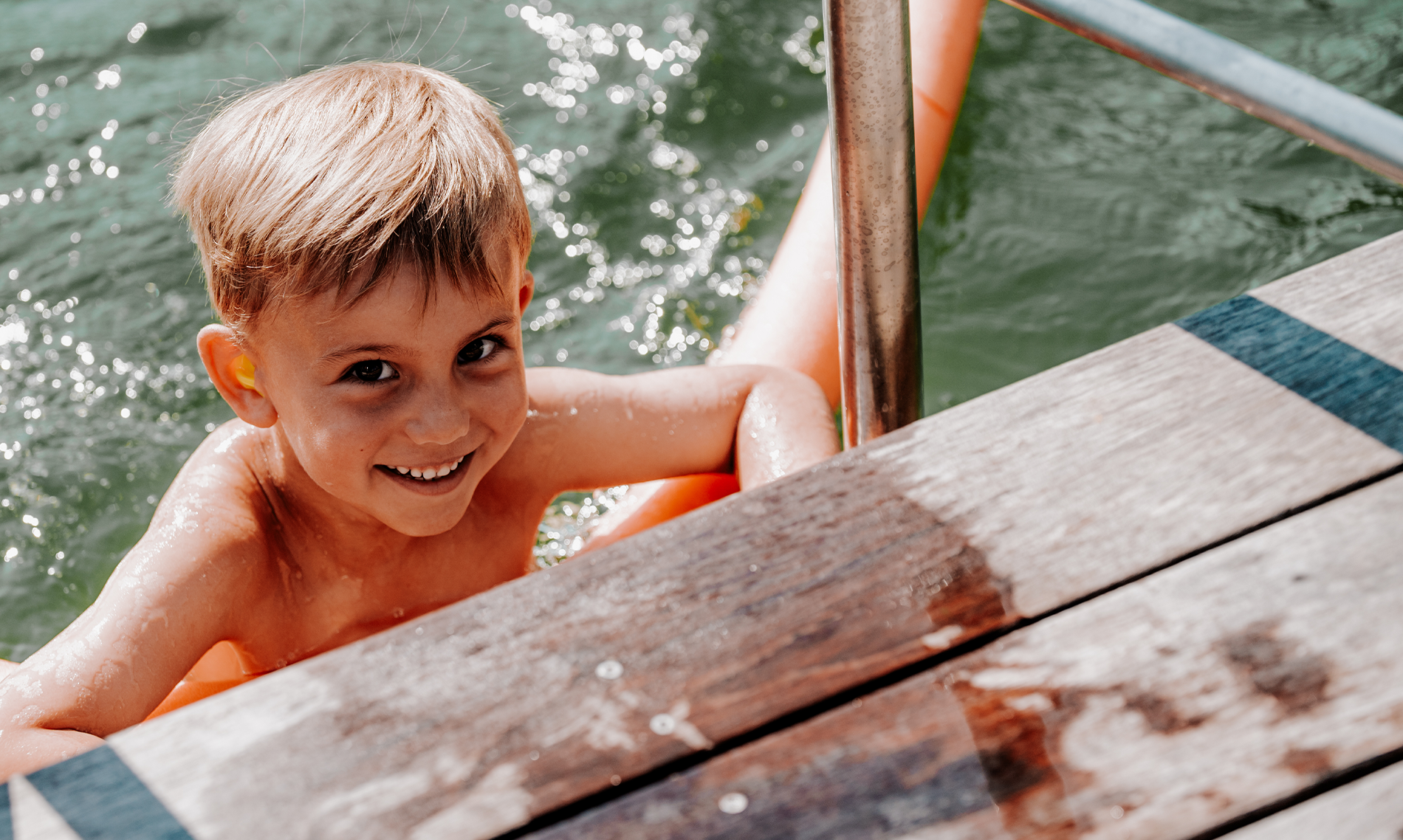 Smiling boy swimming in the water, wearing bachmaier® water protection.