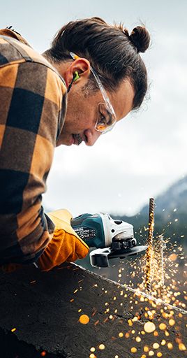Person wearing custom hearing protection while using an angle grinder during DIY and construction work. Custom-fit hearing protection helps reduce exposure to loud power tool noise, providing comfort and reliable hearing protection for workshops, home improvement projects, and industrial environments.