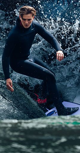 Surfer wearing custom-fit water protection while riding a wave in open water. Custom-fit water protection helps prevent water from entering the ear canal and provides a secure, comfortable fit for surfing, water sports, and extended time in the water.