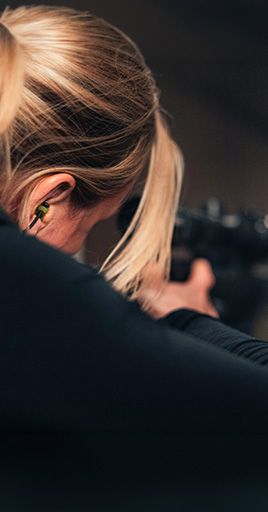 Person using custom hearing protection while practicing shooting sports. Custom-fit hearing protection helps reduce exposure to high-impact impulse noise from firearms while providing comfort and reliable hearing protection for shooting ranges and hunting activities.