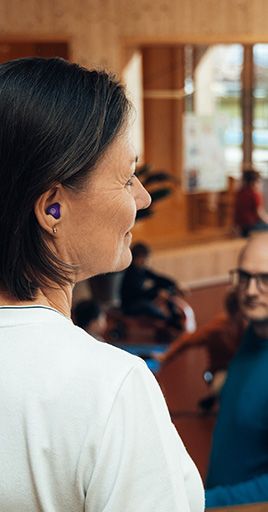 Person wearing custom hearing protection while supervising a group in an educational environment. Custom-fit hearing protection helps reduce everyday noise levels while maintaining clear speech understanding, making it ideal for teachers, childcare professionals, and other communication-focused workplaces.