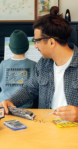 Person wearing custom hearing protection while working on a creative hobby project at a table indoors. Custom-fit hearing protection helps reduce distracting background noise and supports better concentration, making it ideal for hobbies, creative activities, learning environments, and focused work.