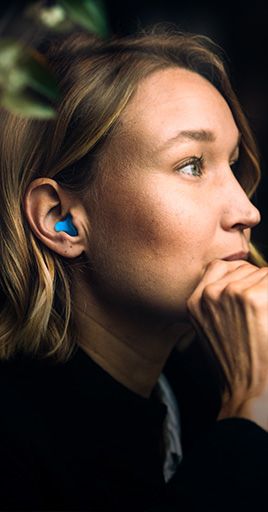 Person wearing custom hearing protection while concentrating in a quiet indoor environment. Custom-fit hearing protection helps reduce distracting background noise and supports focus, concentration, and productivity, making it ideal for studying, office work, remote work, and other focus-intensive tasks.