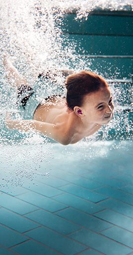 Child swimming underwater while wearing customfit water protection designed for water activities. Custom-fit water protection helps prevent water from entering the ears and provides reliable comfort and protection for swimming, water sports, and regular pool use.